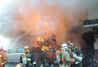 写真：火炎噴出直前の火災室に放水する消防隊